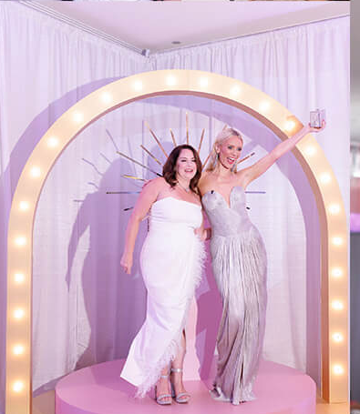 Two women celebrating under the lit arch
