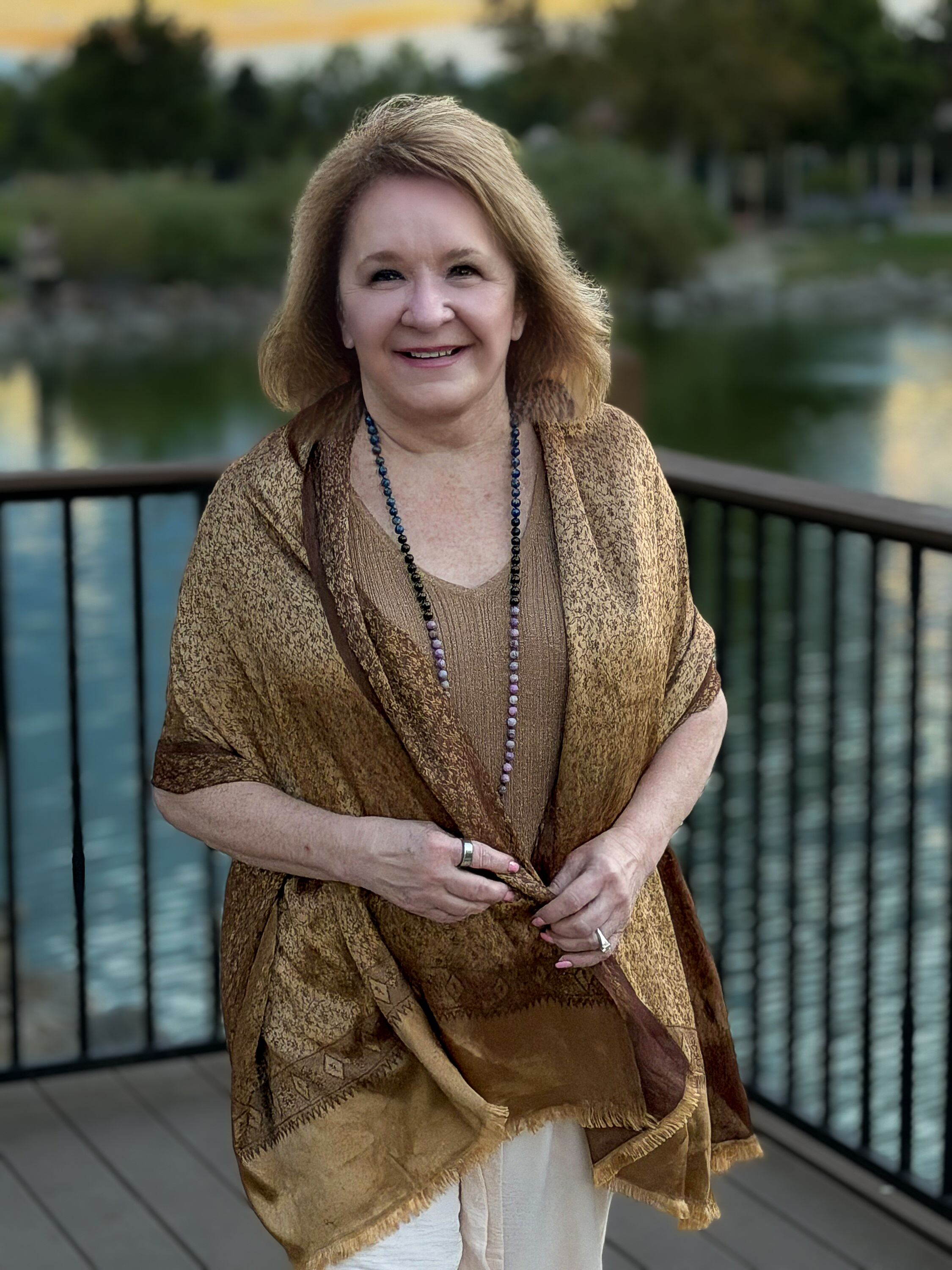 Deb Sheppard standing beside the water in warm evening light