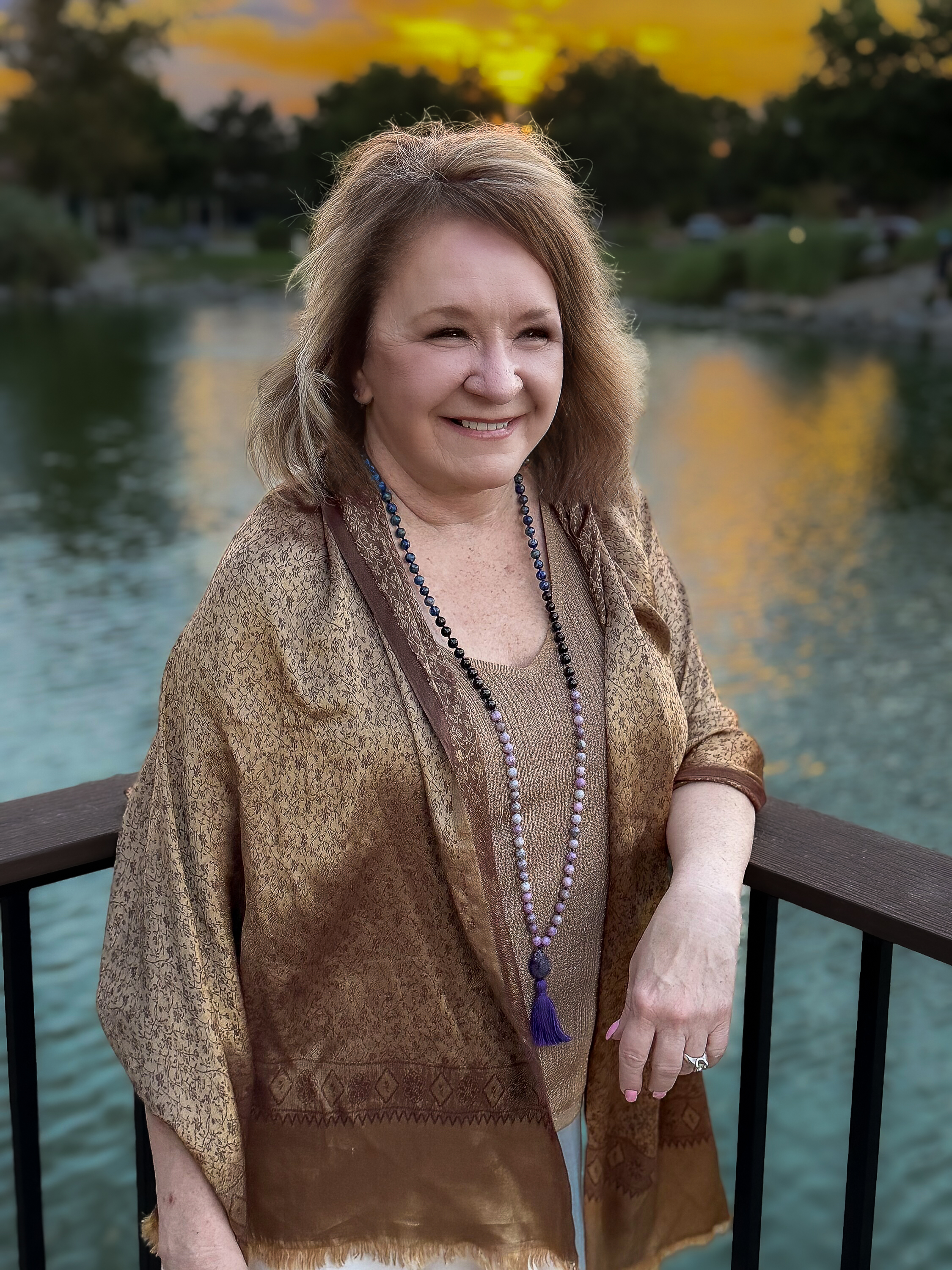 Deb Sheppard smiling beside the water at sunset