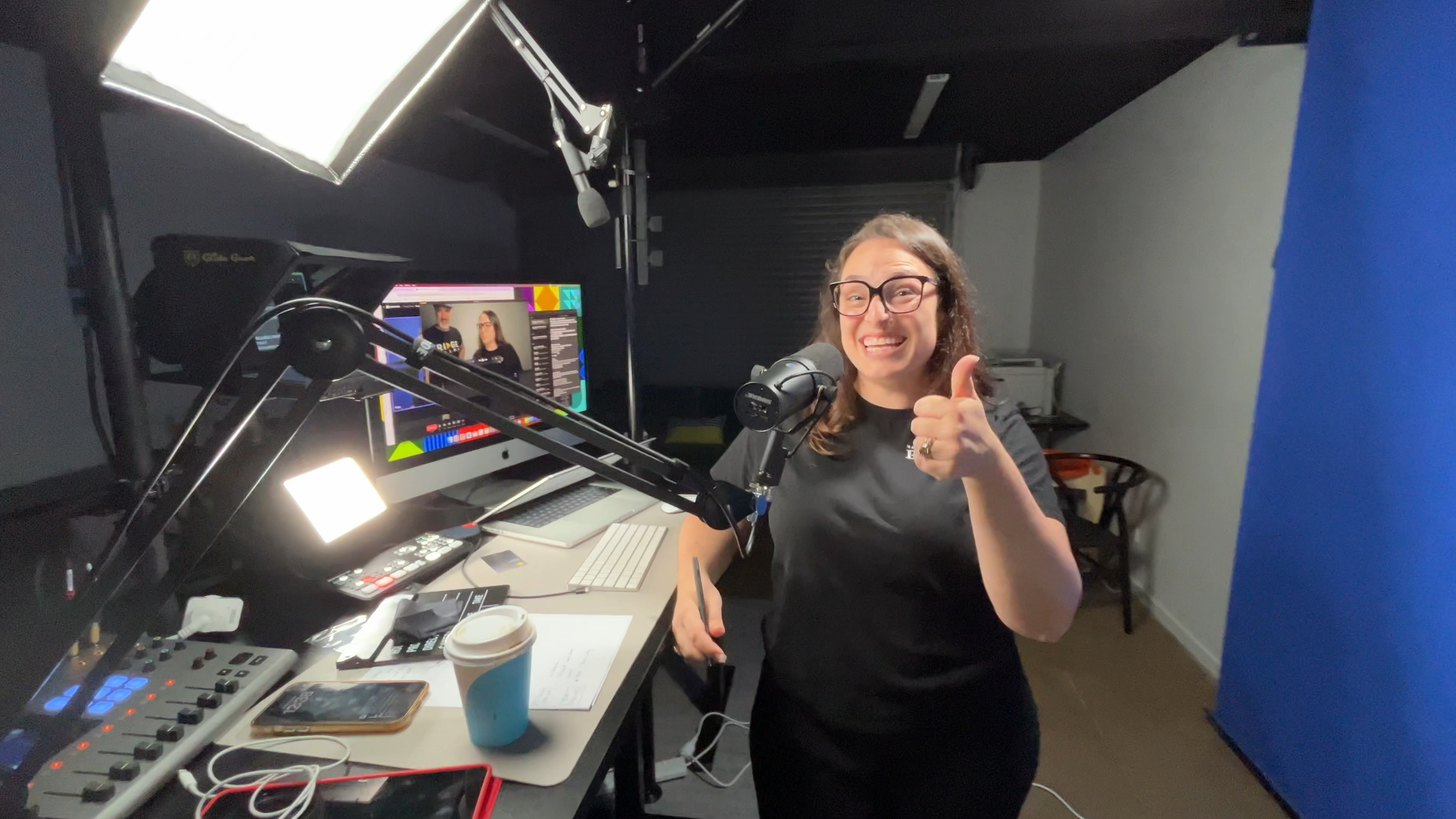 A client recording in her garage against a blue backdrop, giving a thumbs up