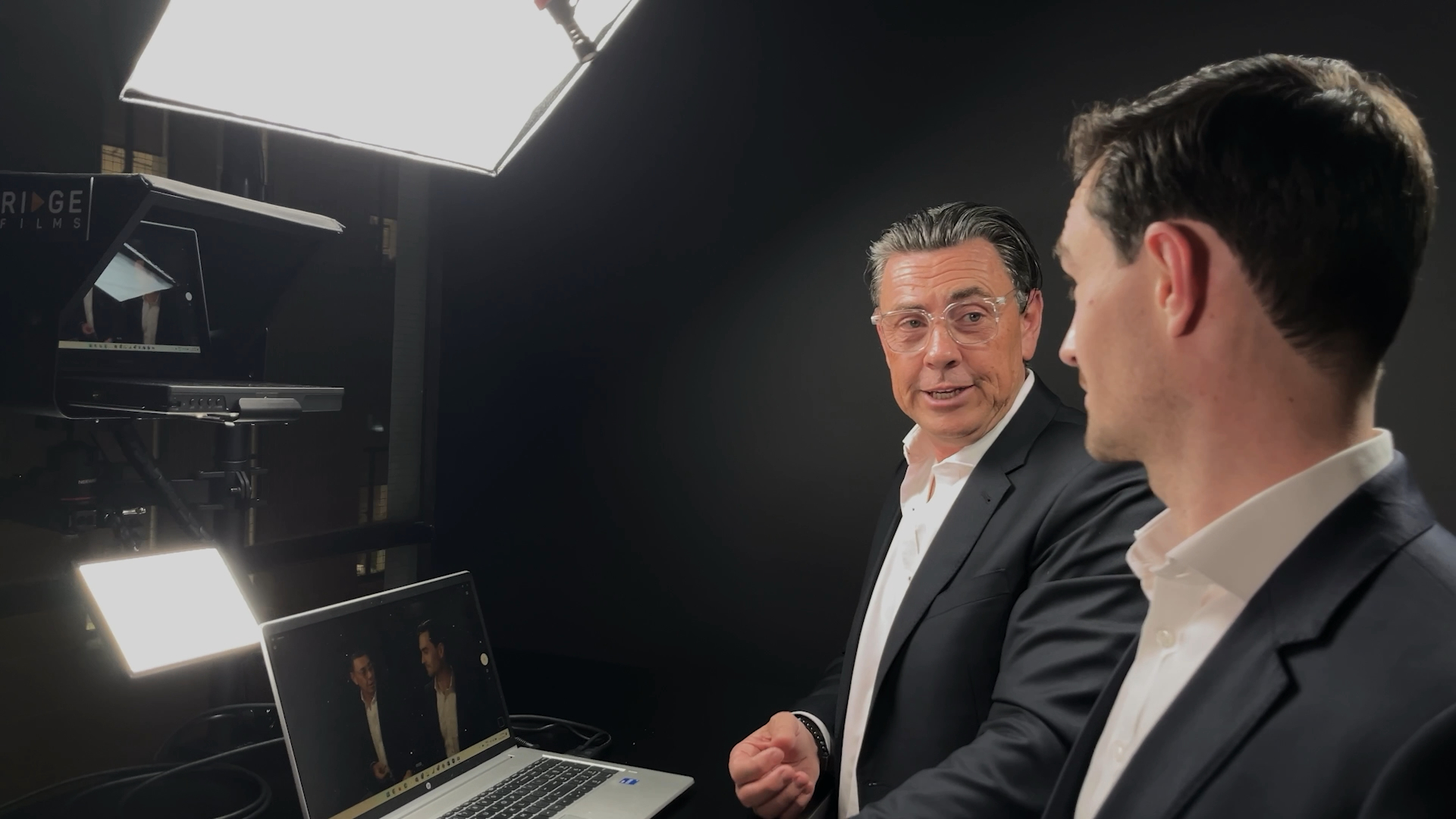 Two clients reviewing playback on the studio monitor