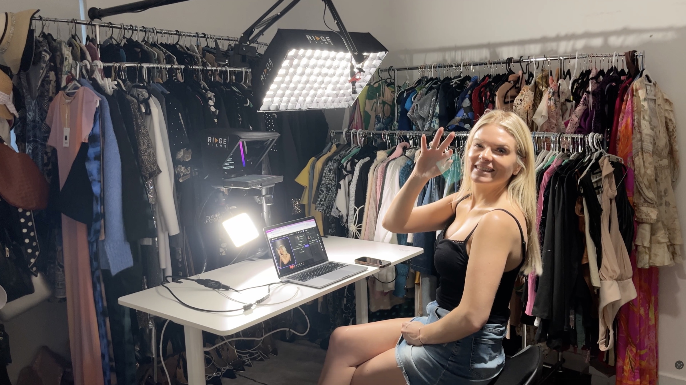 A client smiling and waving into her desktop studio, set up in a walk-in wardrobe