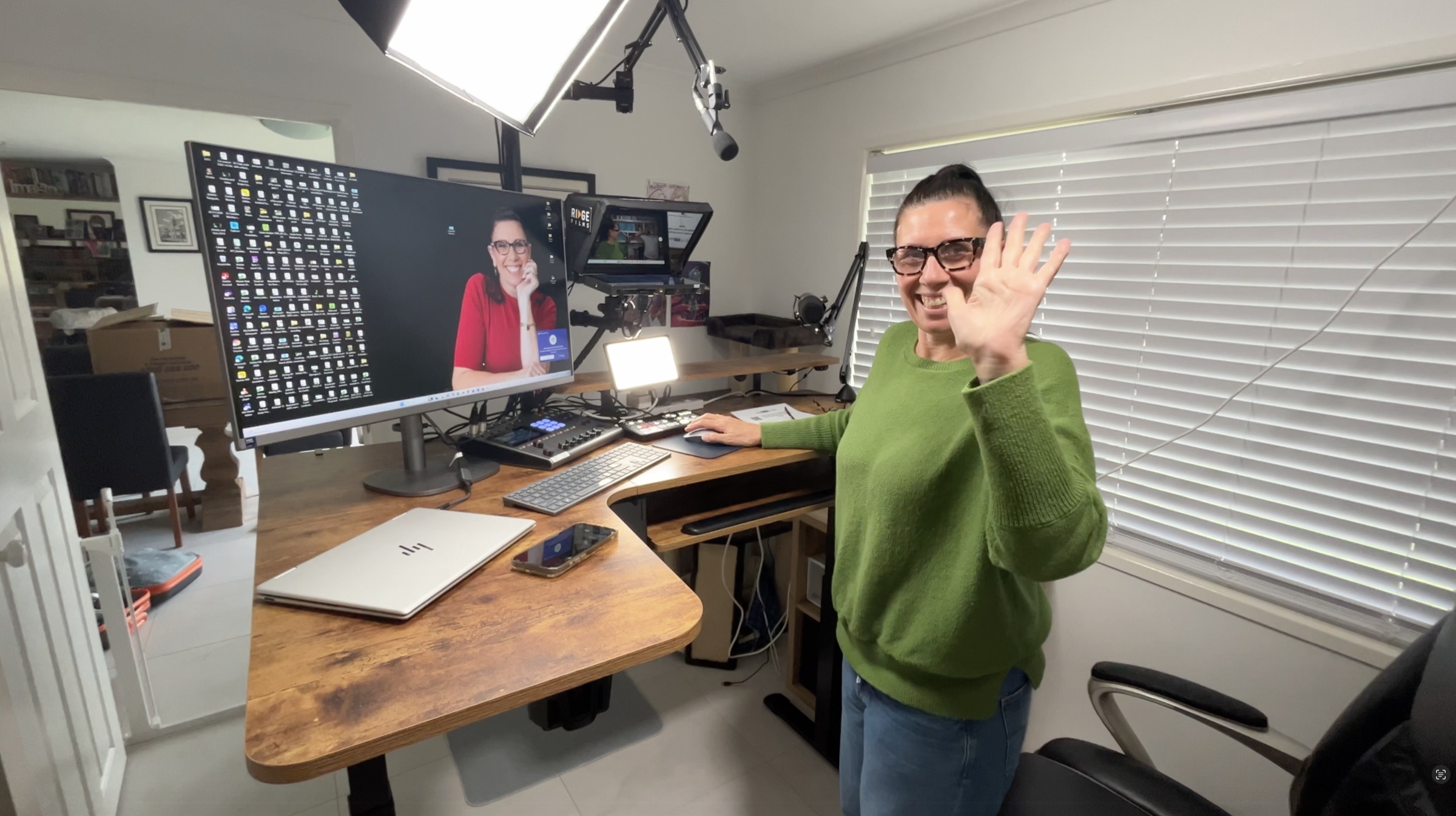 A client waving and smiling into her desktop studio setup