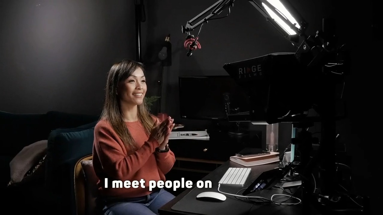 A client delivering a piece to camera in a dark studio room