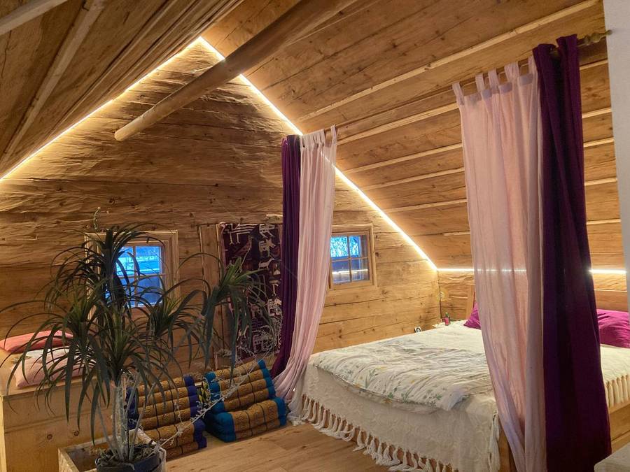 Schlafzimmer mit Holzwänden und Bett mit Vorhang