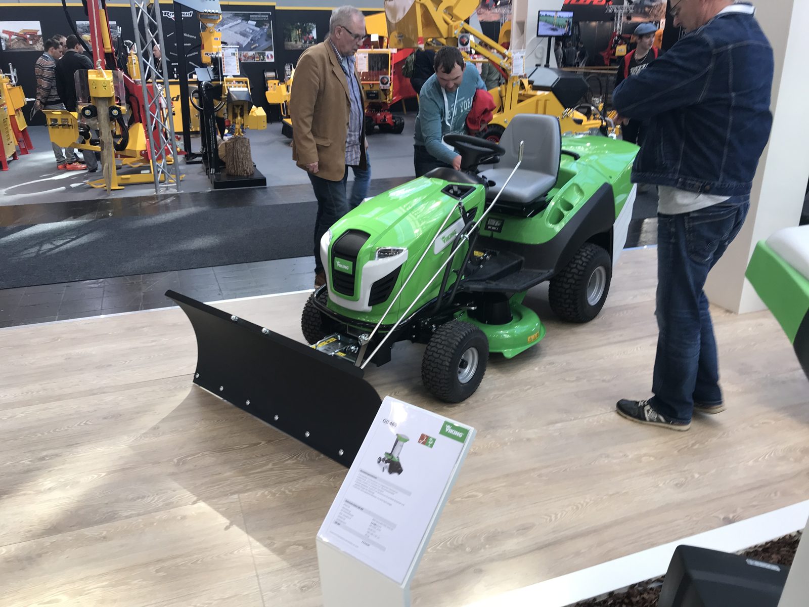 A riding mower displayed with a front-mounted snow blade.