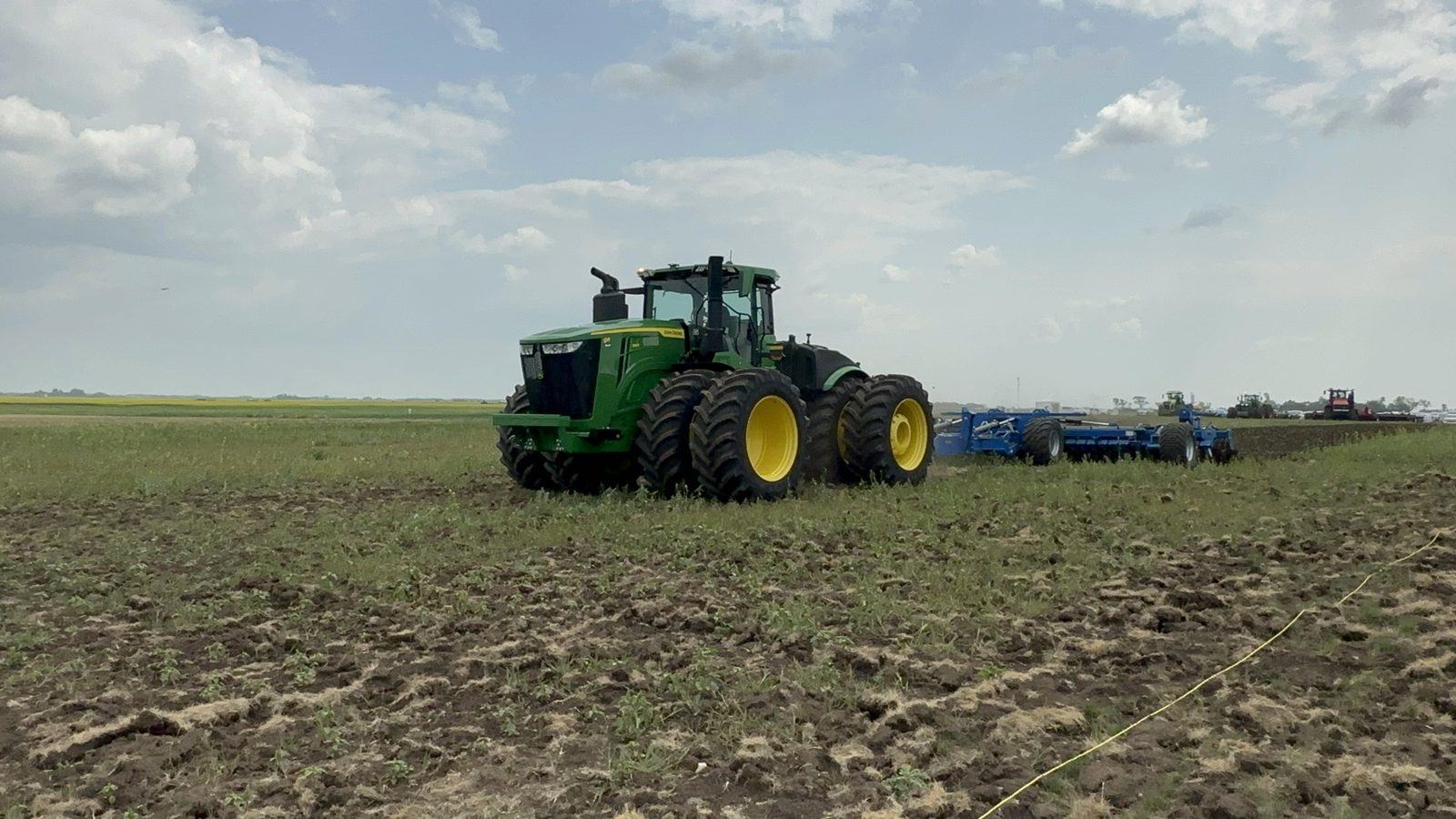 A John Deere tractor working with a wide tillage implement.