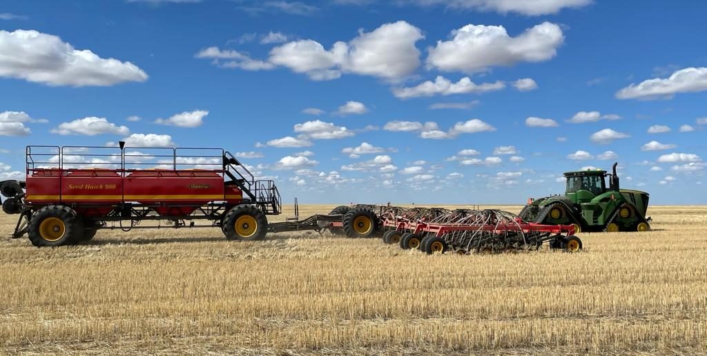 A tracked John Deere tractor with a Väderstad Seed Hawk seeding system.