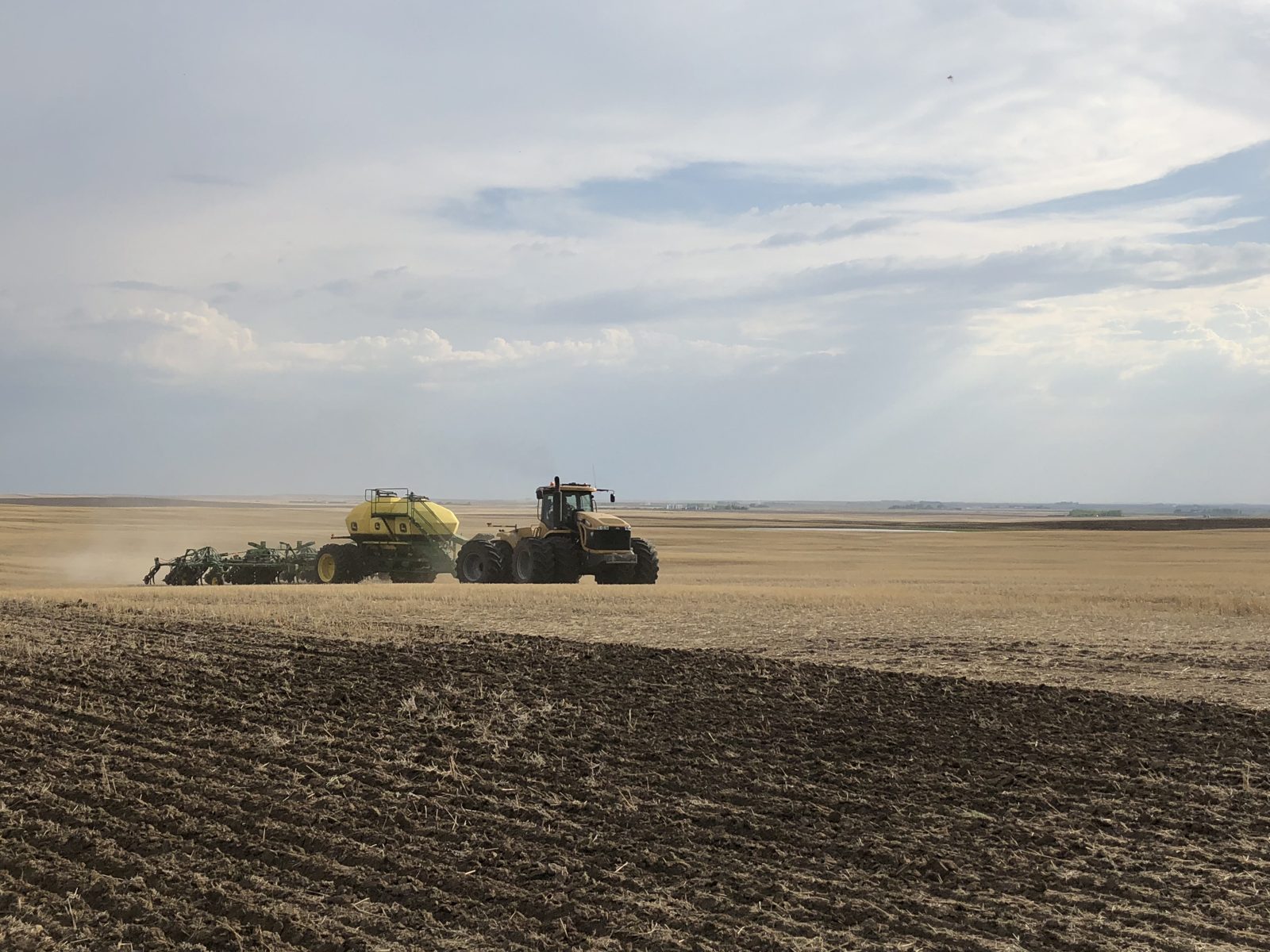 An articulated Challenger tractor with John Deere air-seeding equipment.