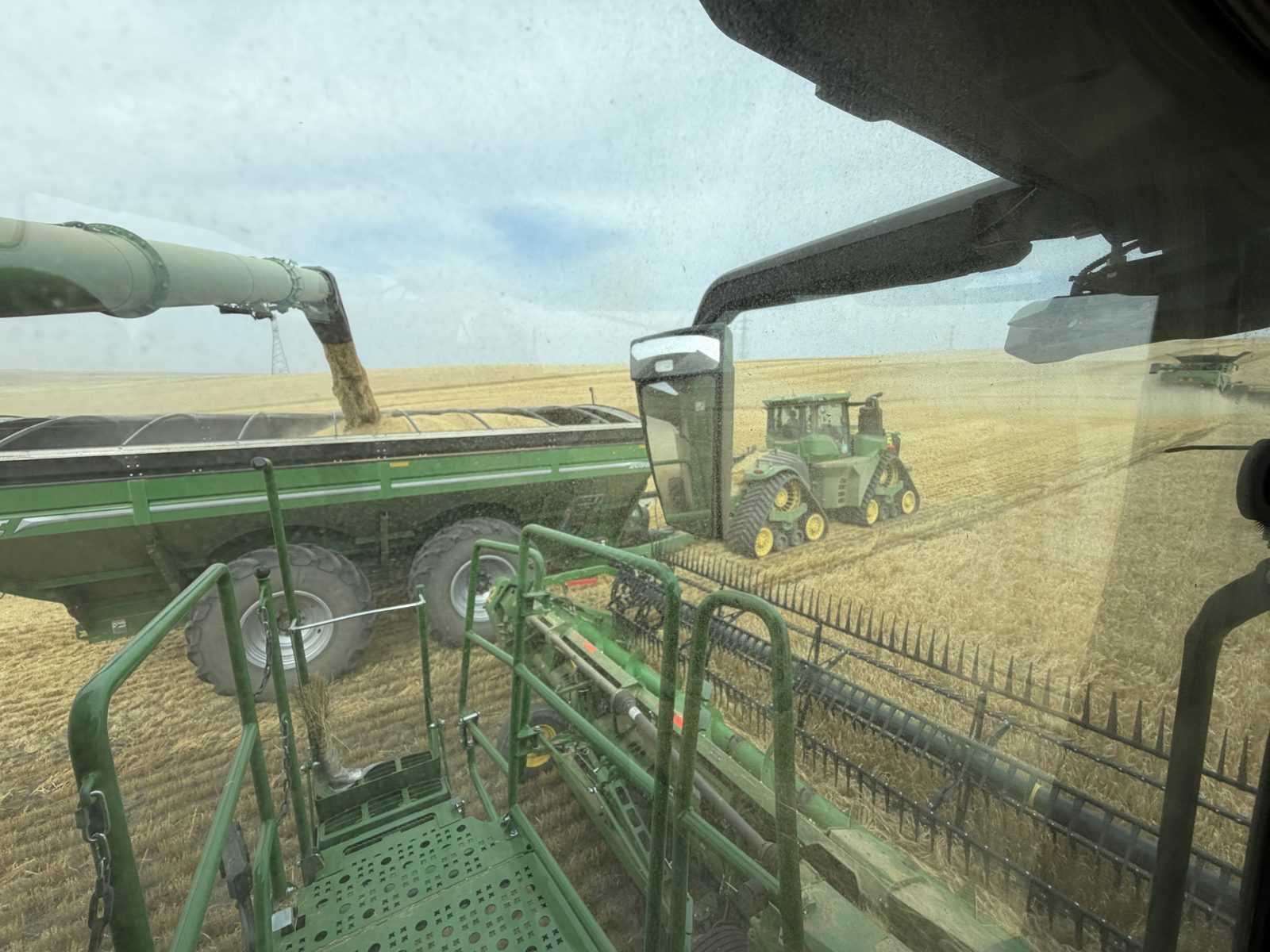 A cab-side view of a tracked tractor and Brent grain cart.