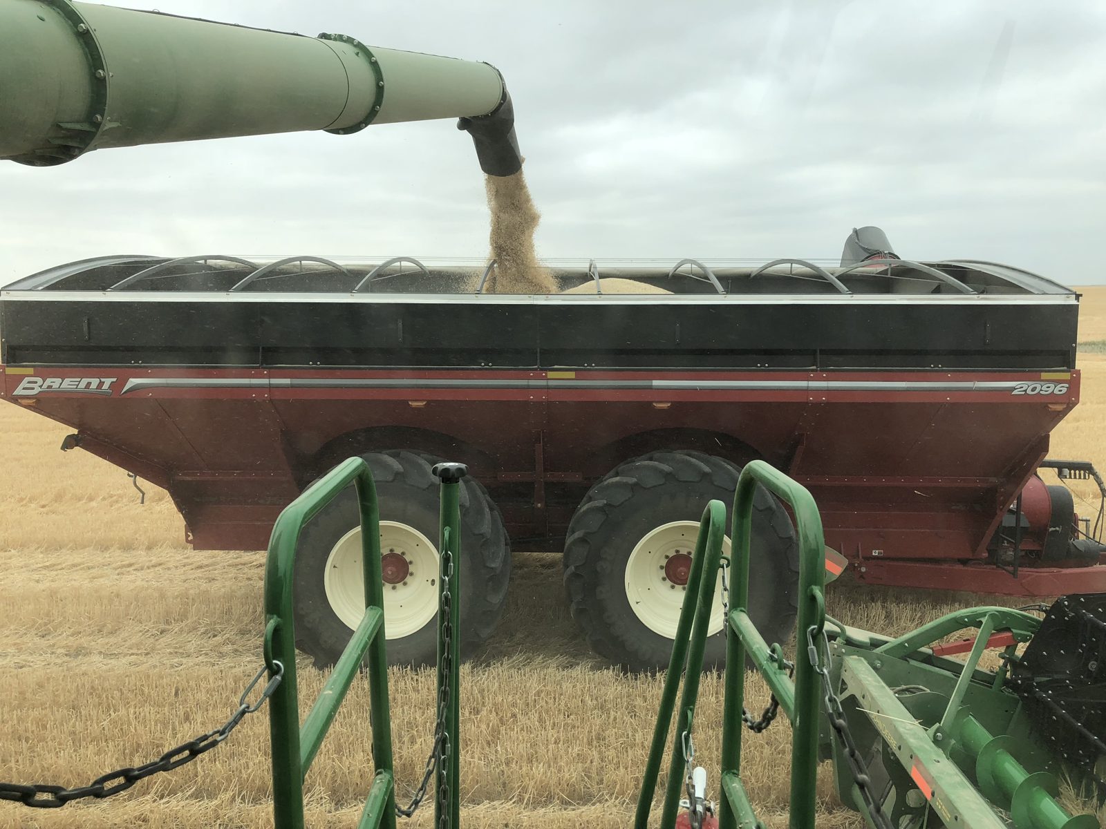 A combine unloading into a Brent 2096 grain cart.