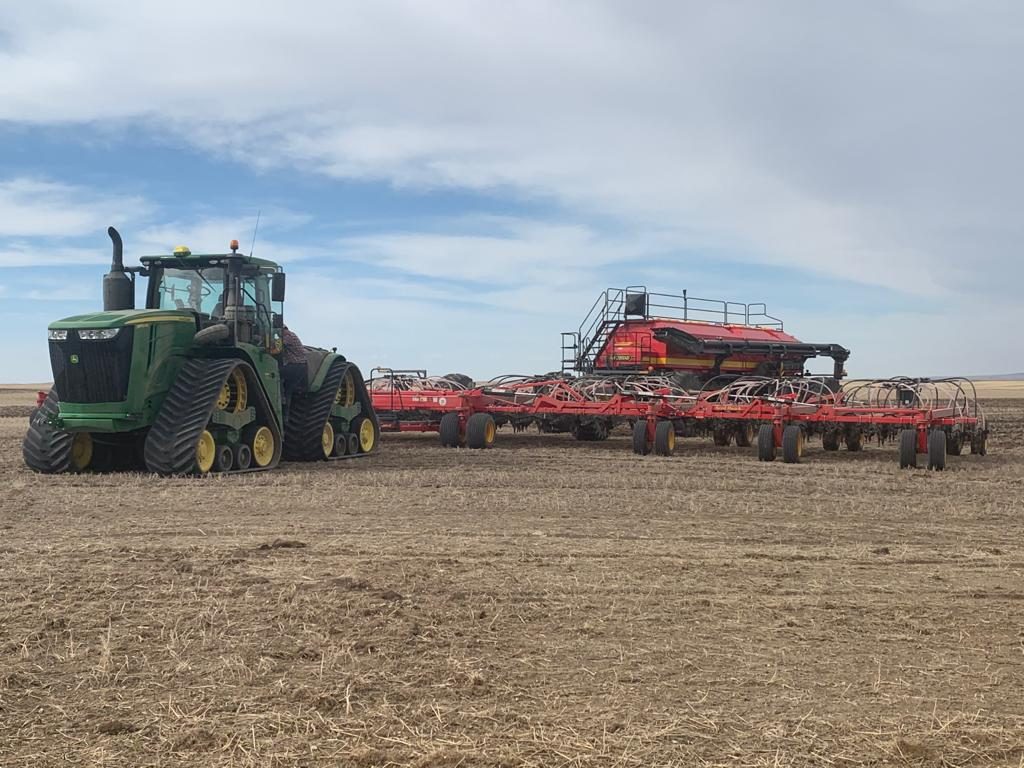A four-track John Deere tractor with Väderstad seeding equipment.