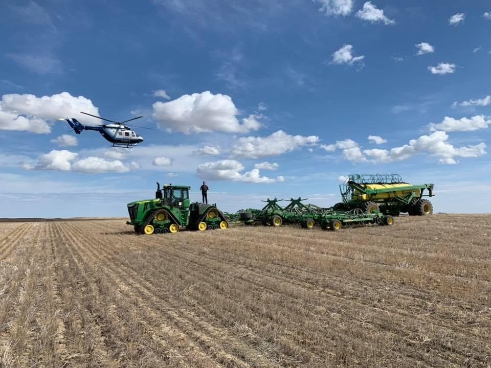 Seeding equipment in the field with a helicopter overhead.