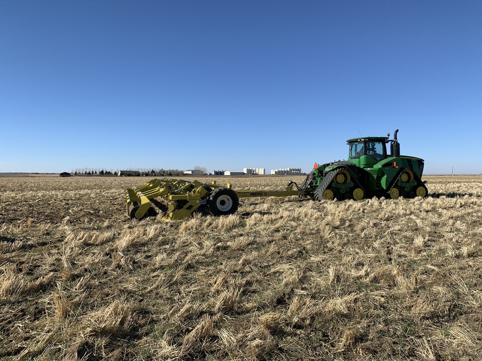 A John Deere tractor pulling a Degelman Pro-Till 40 tillage implement.