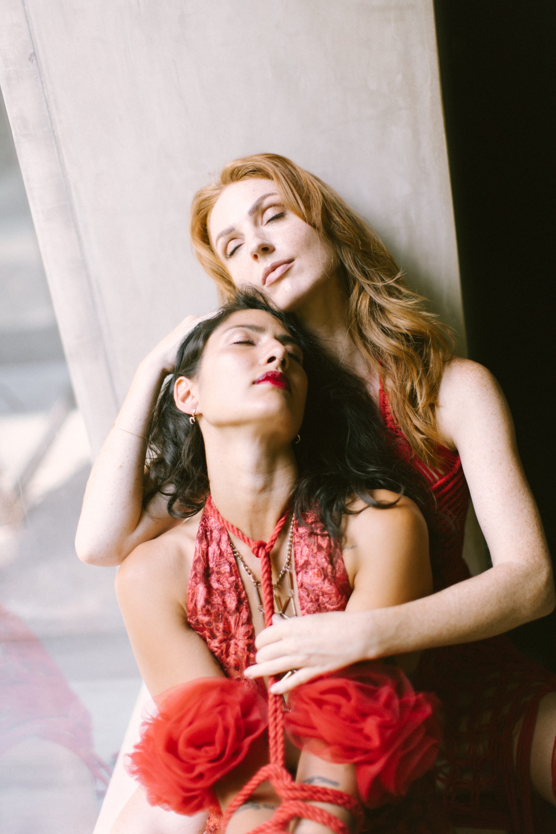 Two women dressed in red resting together