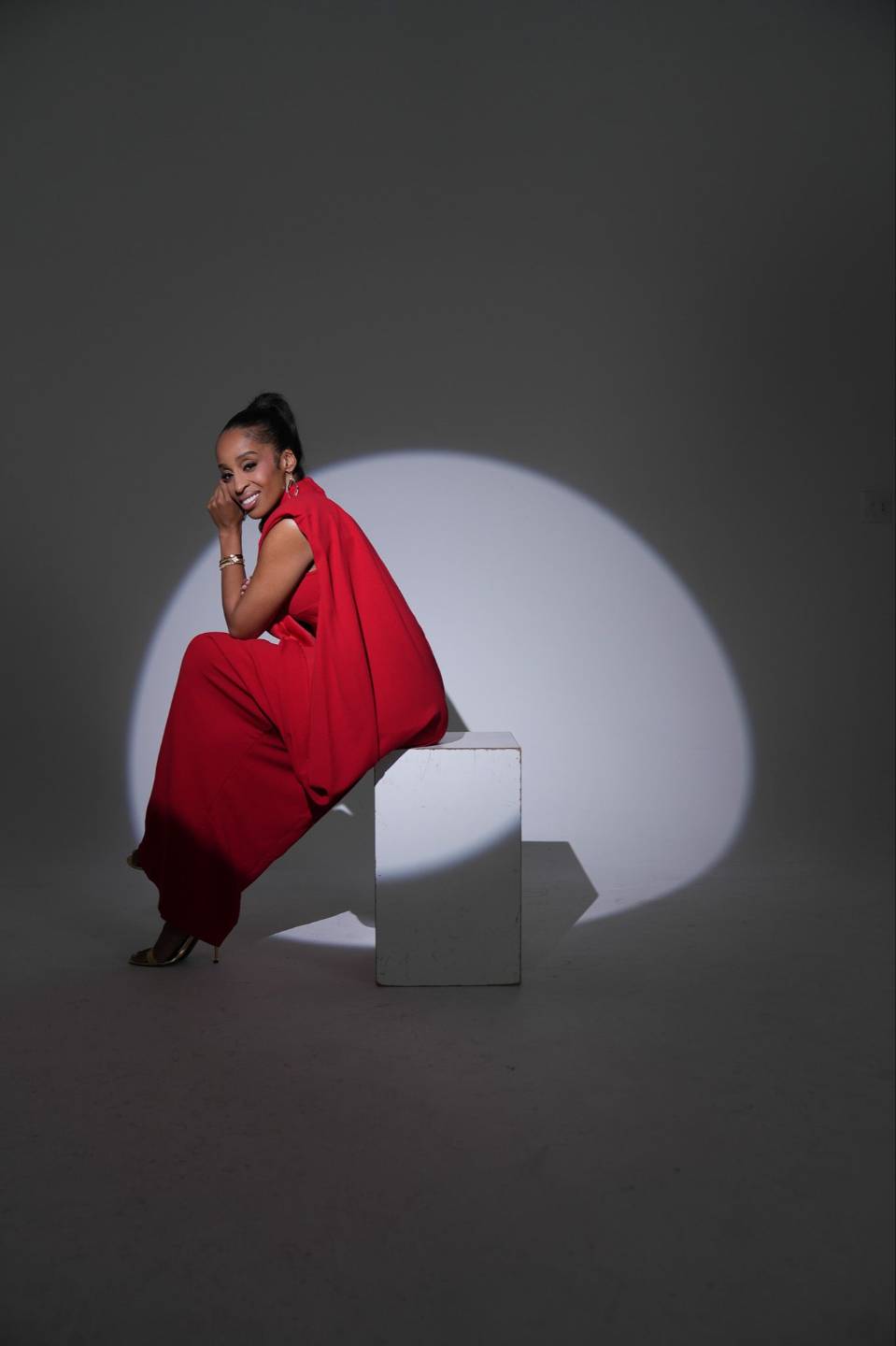 Dr. Simone Ellis in a red outfit, seated in a studio portrait
