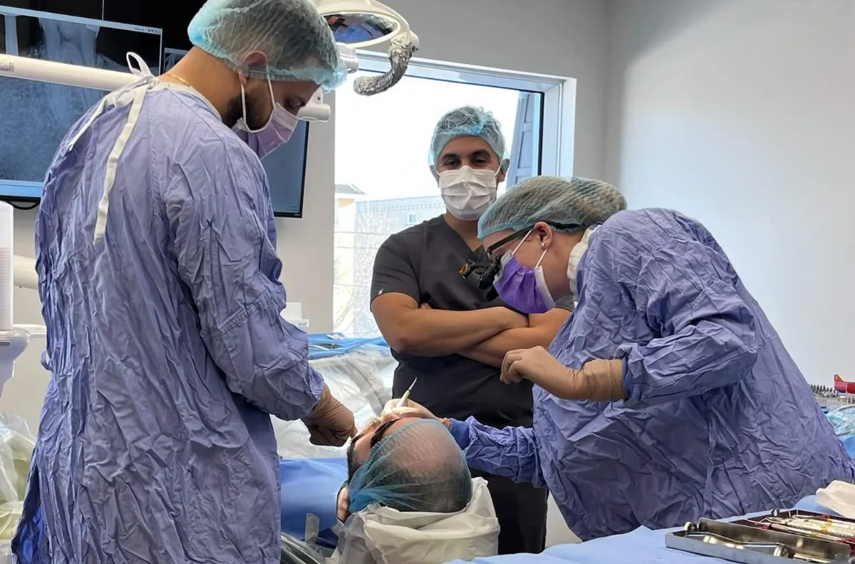 A surgical team in sterile gowns performing full-arch implant surgery