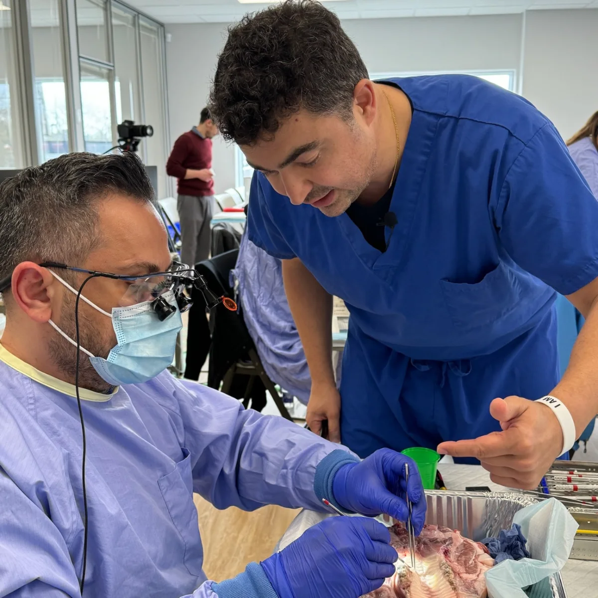 Dentist practicing a bone grafting procedure on a pig-jaw model while a Zeeba periodontist coaches during the hands-on session