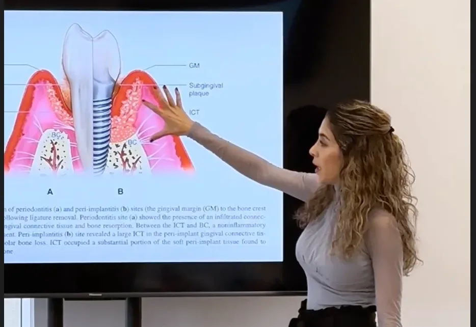 Dr. Sara Behmanesh lecturing in front of a screen showing a diagram comparing periodontal and peri-implant tissue