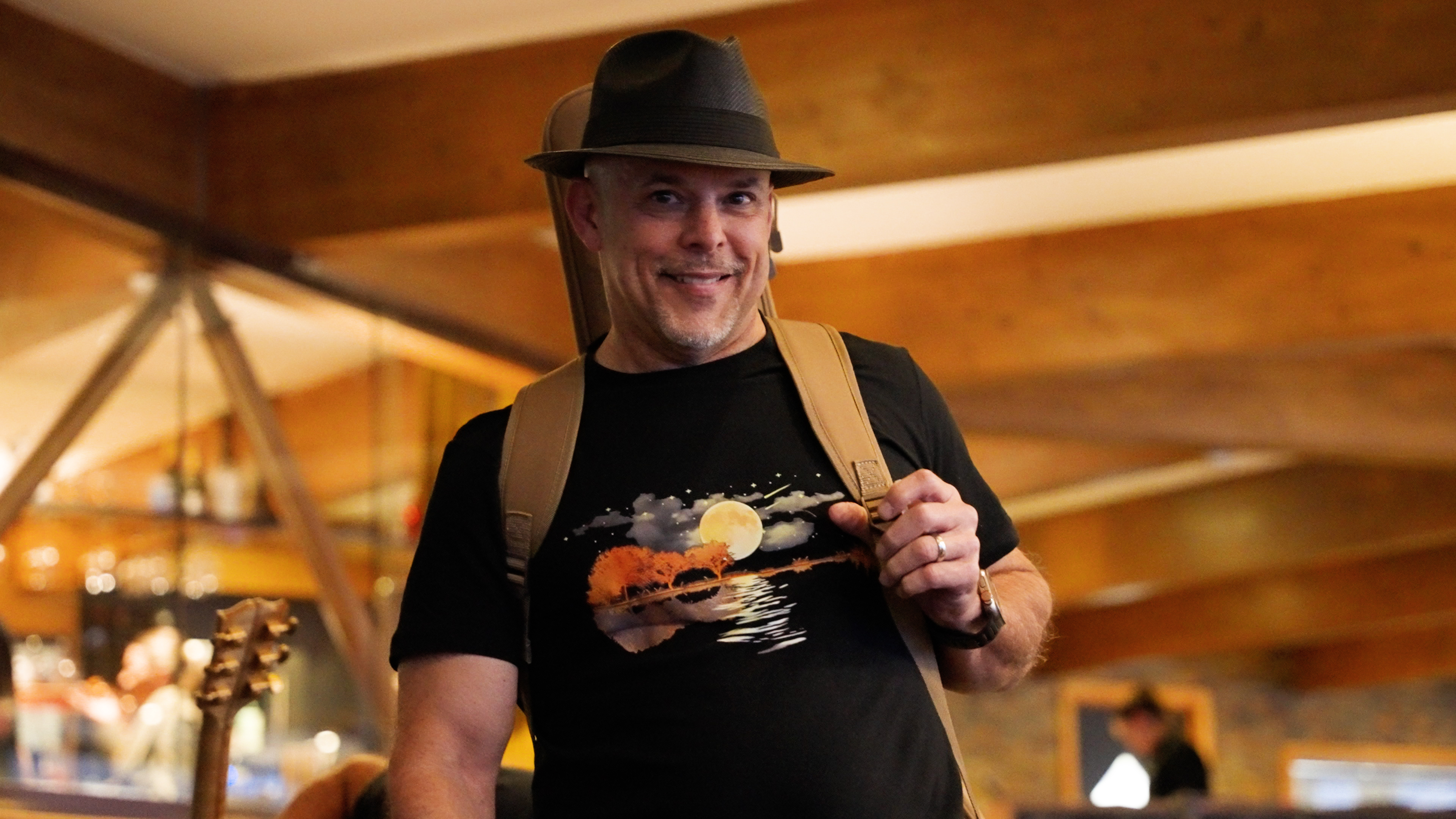 A smiling guest arriving with his guitar on his back