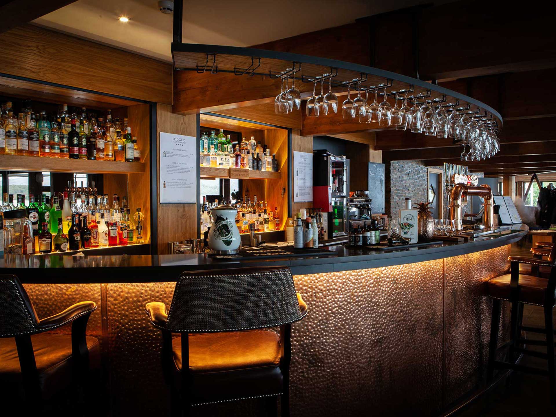 The copper-fronted bar at the Lodge, lit warm above a wall of whisky