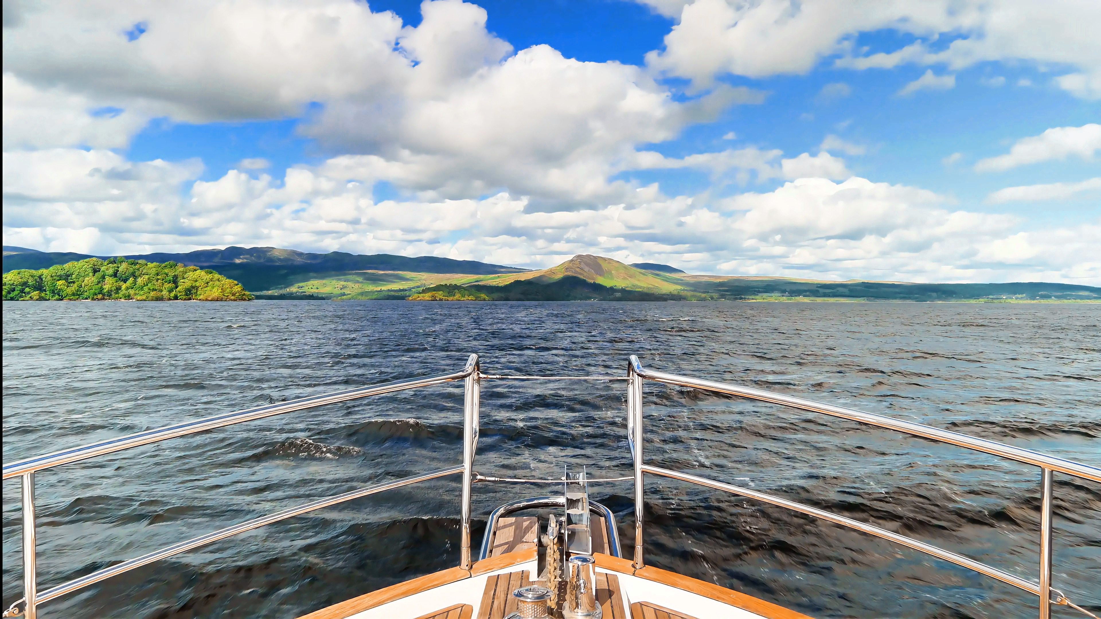 The bow of a boat looking out across Loch Lomond toward the hills