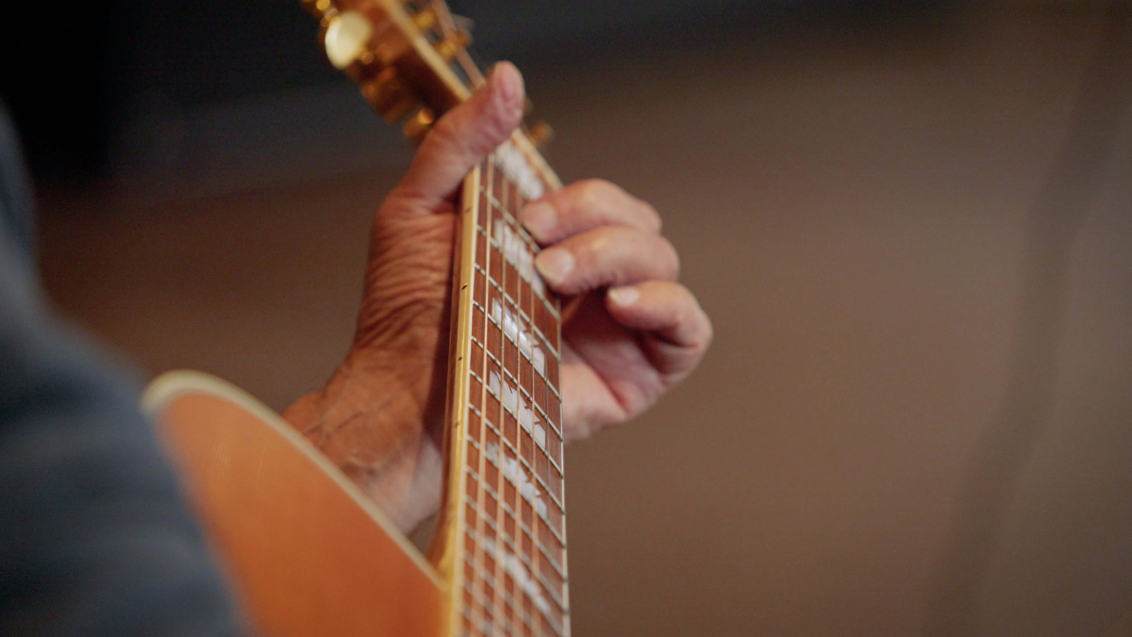 A close view of a hand forming a chord on a guitar fretboard