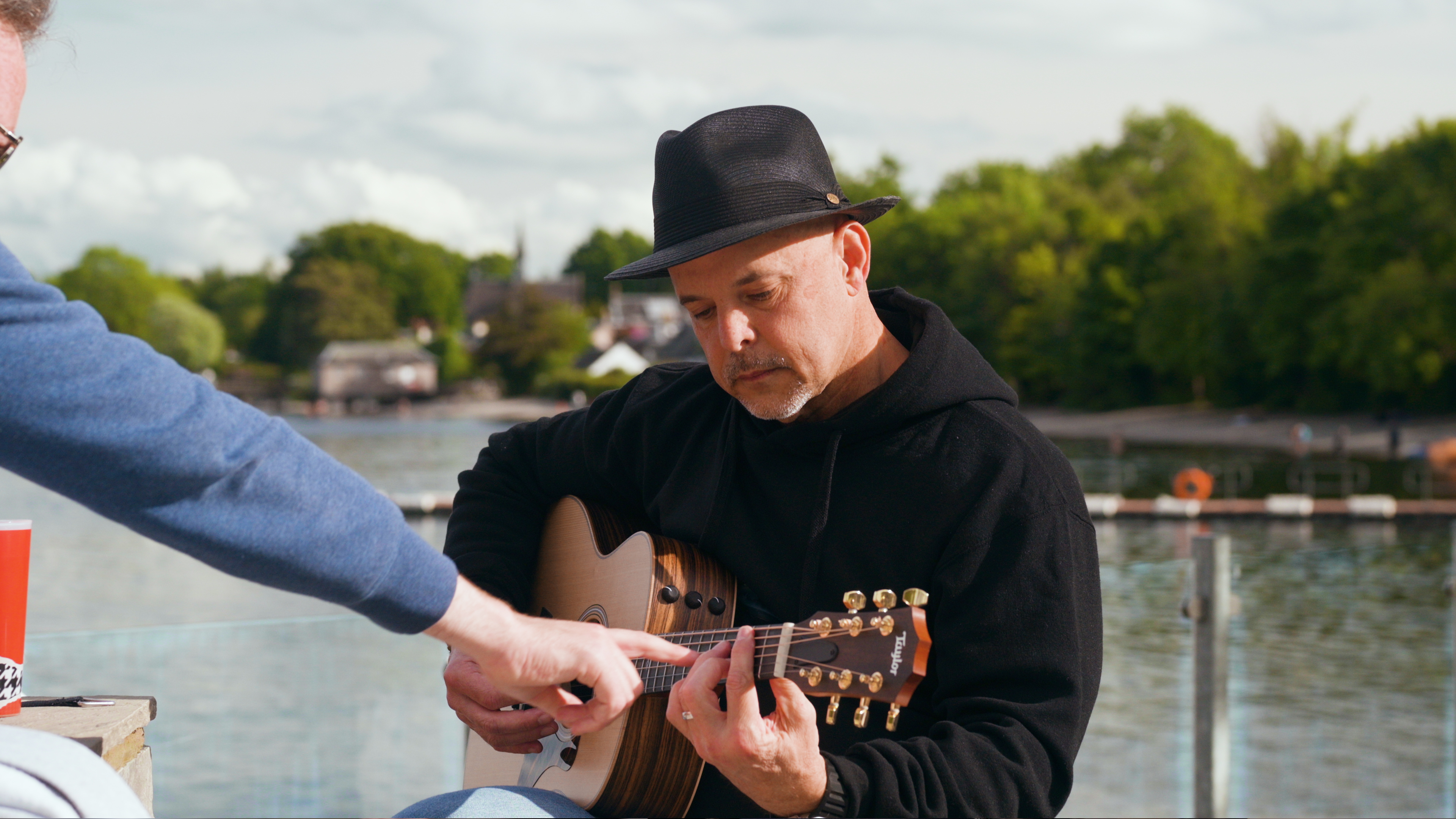 A guest being shown a chord shape on the fretboard beside the loch