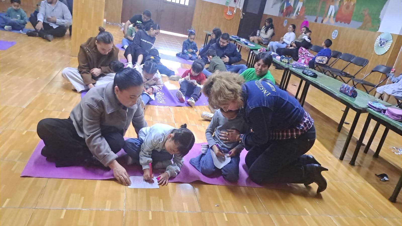 Familias acompañando a los niños en una actividad grupal dentro del salón