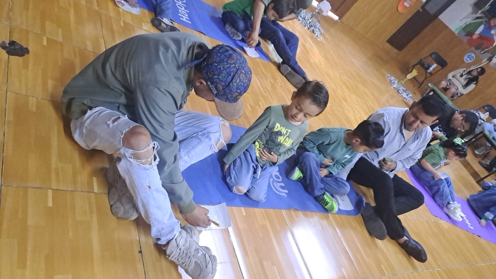 Padres y niños trabajando juntos sobre tapetes en una actividad en el salón