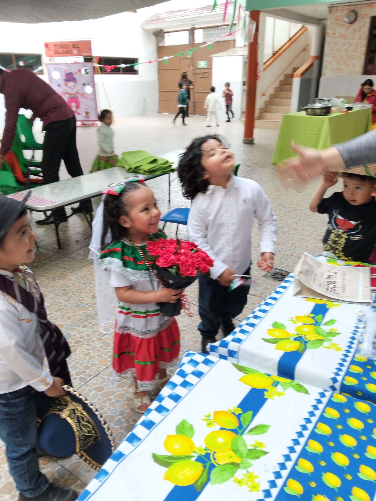 Niña con vestimenta tradicional mexicana y un ramo de flores durante un festival escolar