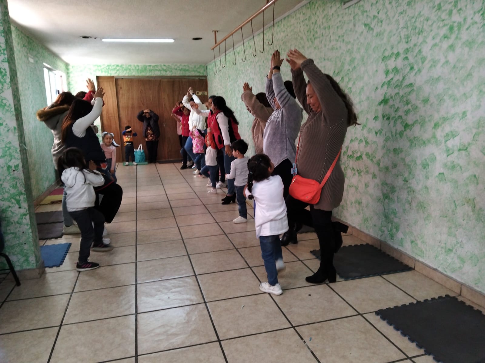 Estudiantes y familias realizando ejercicios de estiramiento en el pasillo del instituto
