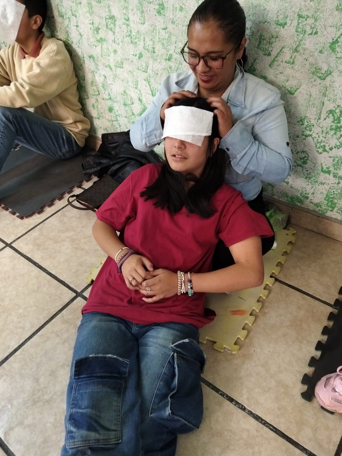 Una madre acompaña a su hija durante una dinámica de confianza con los ojos vendados