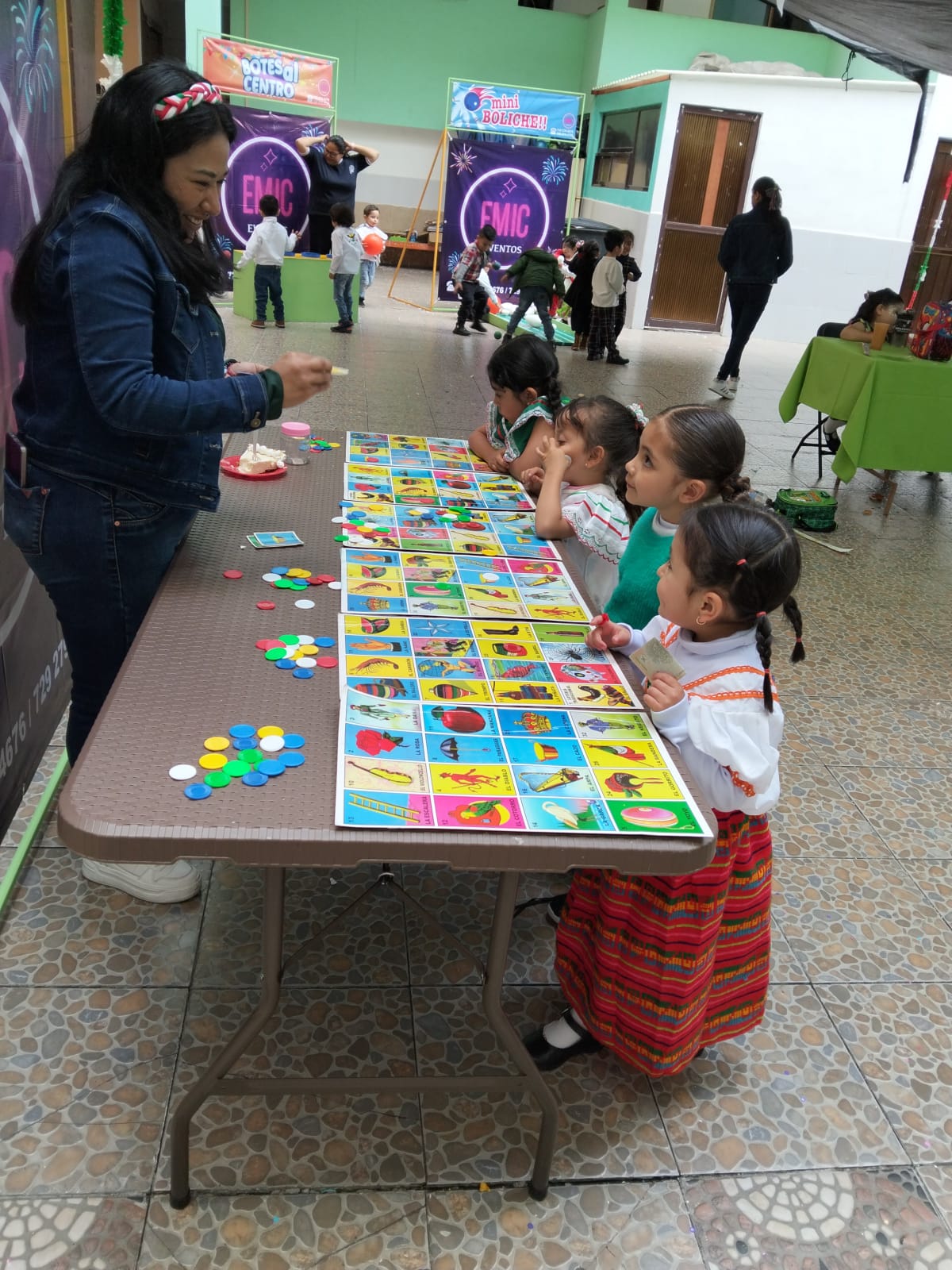 Niñas de preescolar participando en una dinámica de lotería durante un festival escolar