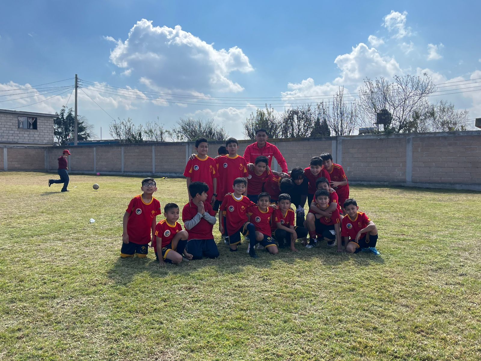Equipo de estudiantes con uniforme deportivo rojo reunidos en la cancha del instituto