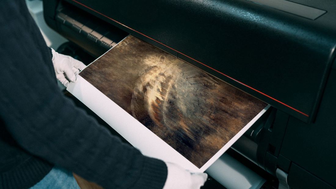 A gloved hand lifting a fine art print from a large format printer