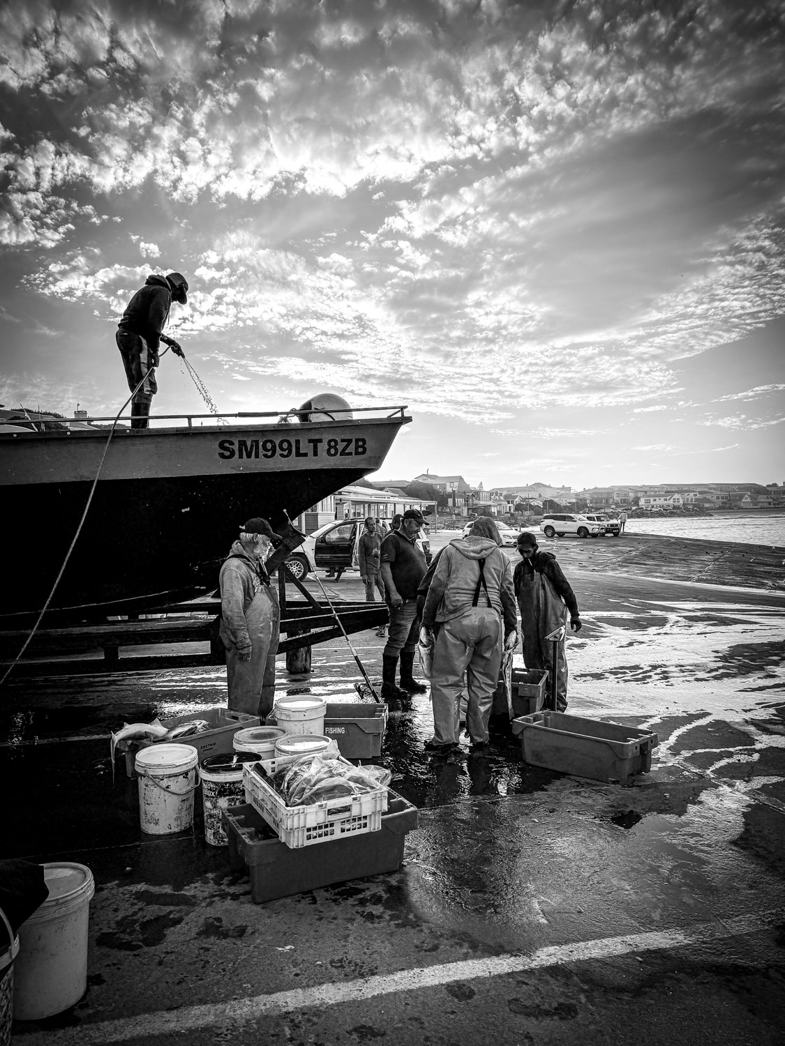 Black and white photograph of fishermen unloading a boat on the slipway