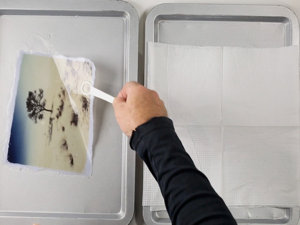 A photographic image being lifted in a tray of liquid, the luminance transfer technique