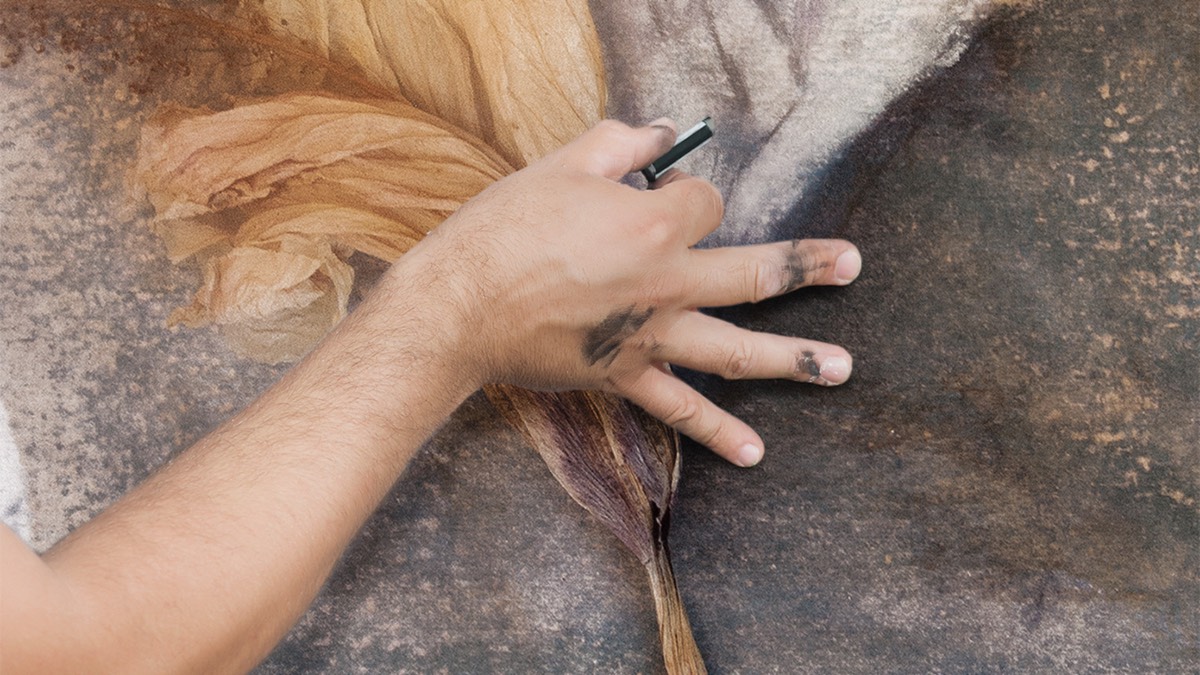 A hand blending dry pastel into the surface of a photographic image, the pastel blend technique
