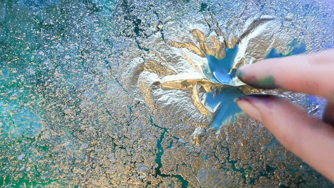 Fingers working wet colour across a fluid abstract surface
