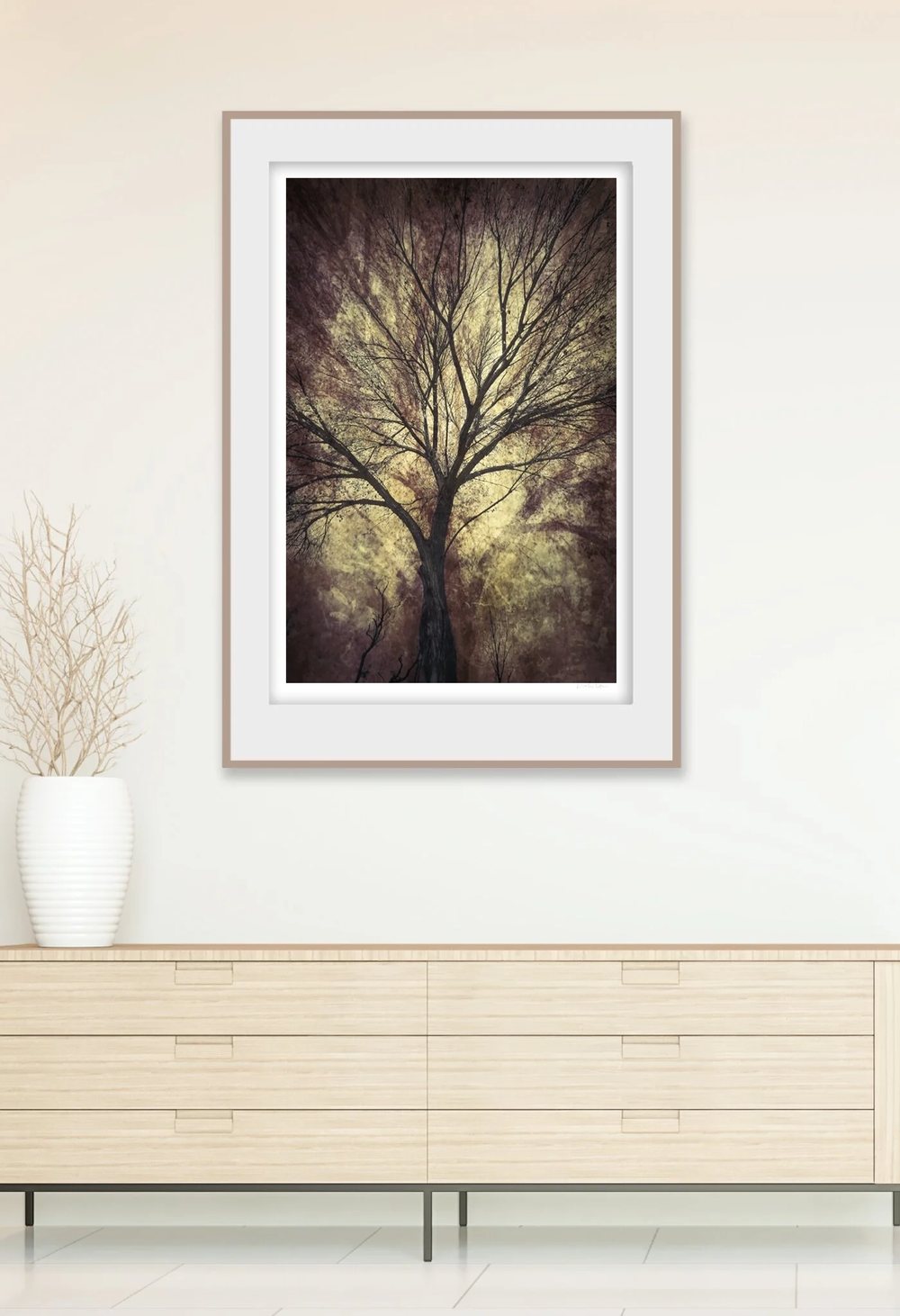 A tall framed tree study on a wall above a sideboard