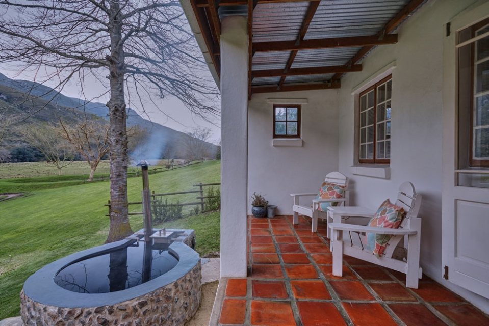 An outdoor heated tub on the veranda looking out at the mountain