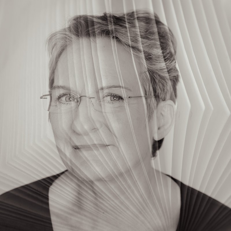 Andrea Armbruester, a black and white portrait behind fine folded lines
