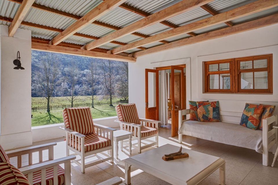 A covered veranda with chairs looking out over the green valley