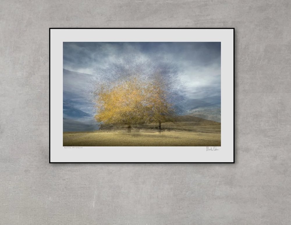A framed golden tree over a mantel in a pale living room