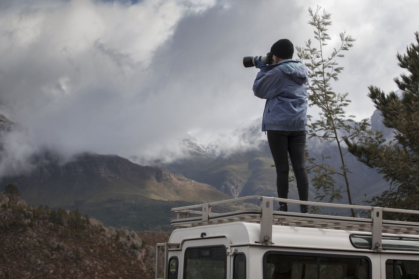 Samantha Lee Osner photographing from the roof of a Land Rover in the mountains