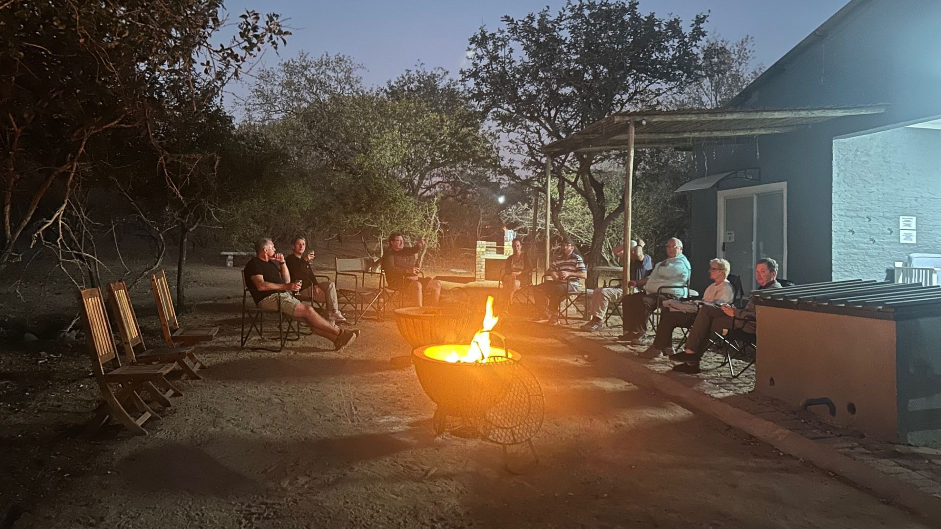 People sitting around a fire in the boma at night under the trees