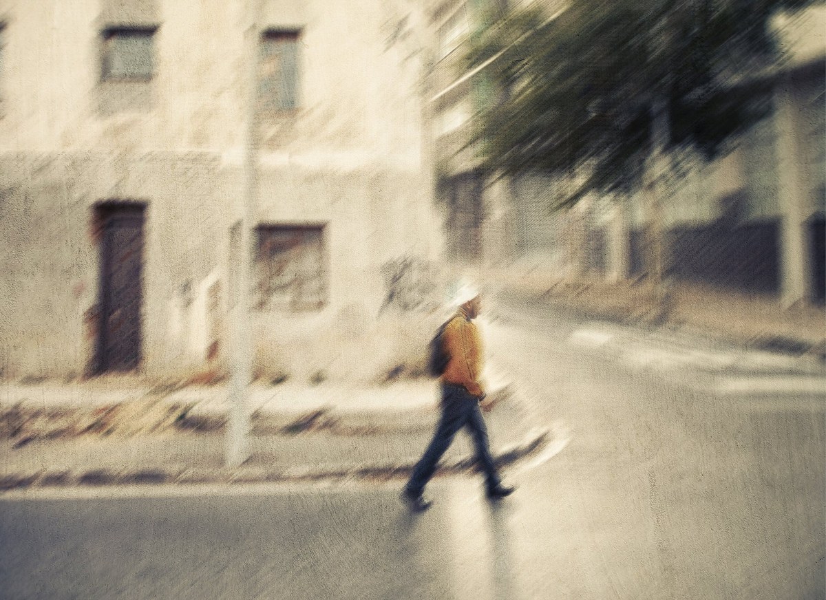 Blurred figure walking past a European street wall