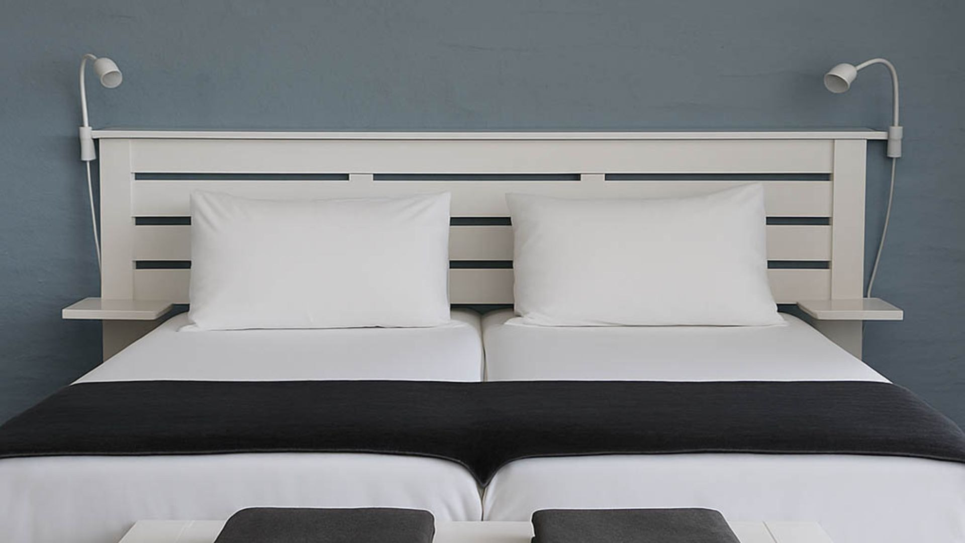 A double bedroom with white linen and grey throws