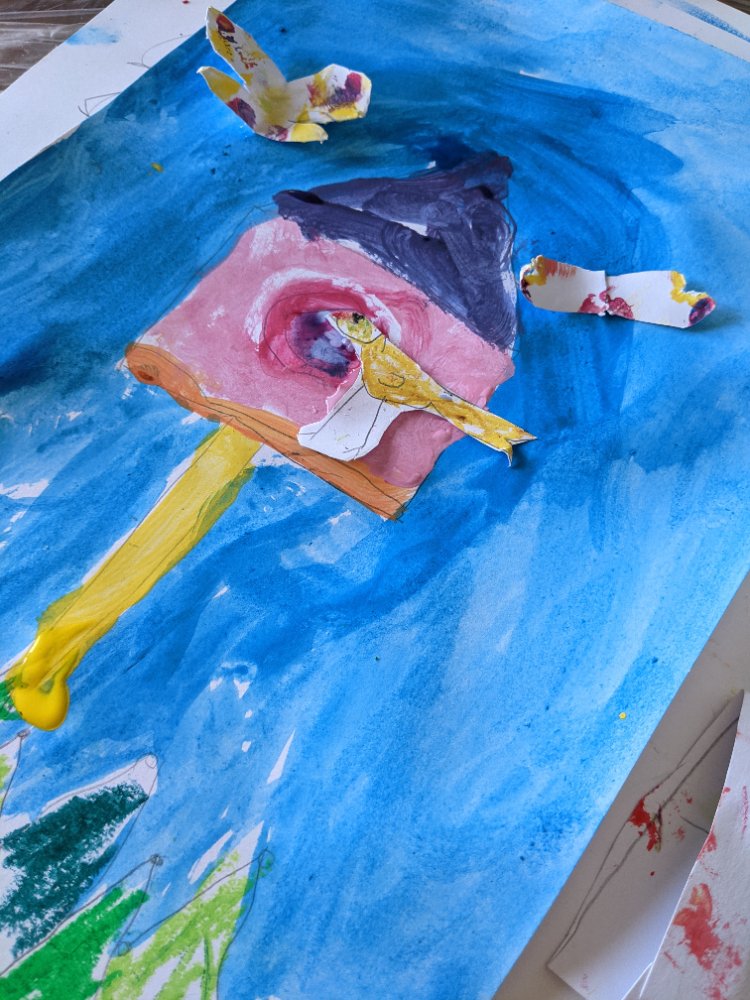 A painted birdhouse scene with cut-paper birds on a blue sky